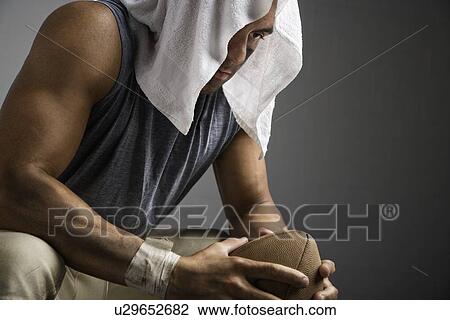 Stock Image - Football player with towel on head holding football. Fotosearch