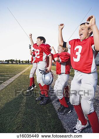 Stock Photo - Football players cheering on sideline. Fotosearch