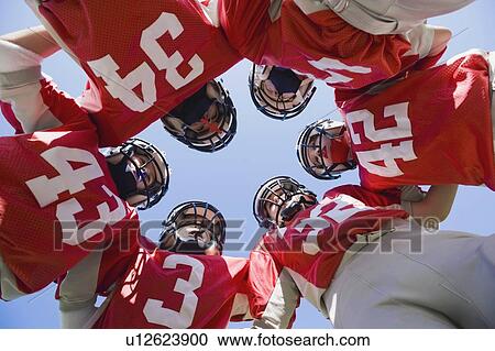 Stock Image - Football players in huddle. Fotosearch