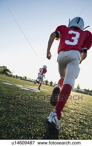 Stock Photo - Football players running on field. Fotosearch
