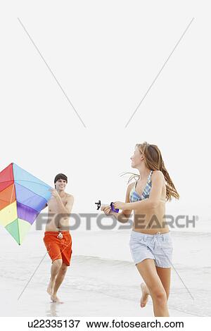Stock Photo - Friends flying kite on beach. Fotosearch