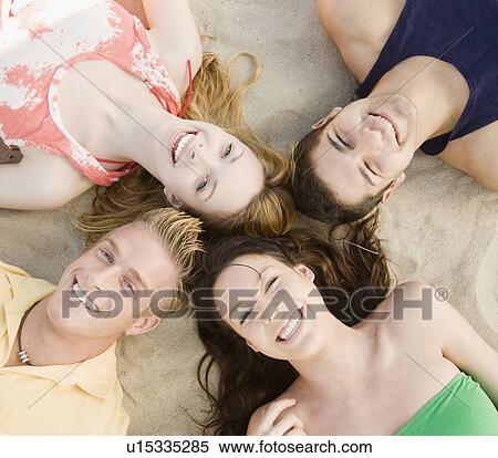 Friends laying on sand View Large Photo Image Stock Photography - Friends laying on sand. Fotosearch