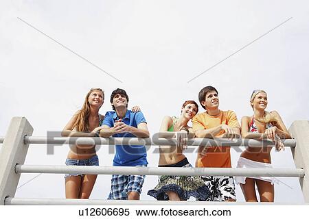 Stock Photography - Friends leaning on boardwalk railing. Fotosearch