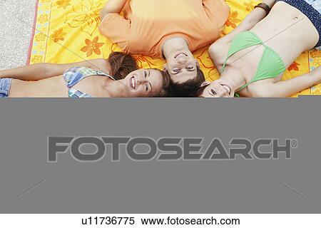 Friends lying down on beach towels View Large Photo Image Stock Photography - Friends lying down on beach towels. Fotosearch