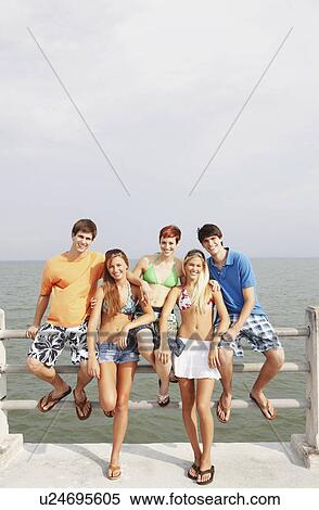 Stock Photography - Friends posing on boardwalk railing. Fotosearch
