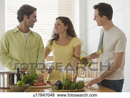 Stock Photo - Friends preparing meal in kitchen. Fotosearch