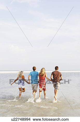 Picture - Friends running in ocean. Fotosearch