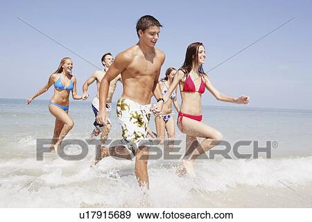 Stock Photo - Friends running in ocean. Fotosearch
