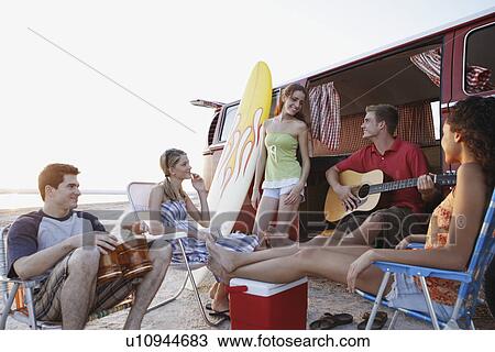 Friends socializing around van on beach View Large Photo Image Stock Image - Friends socializing around van on beach. Fotosearch