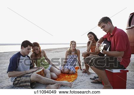 Stock Photo - Friends socializing on beach. Fotosearch