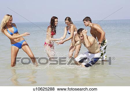 Stock Photo - Friends splashing each other in ocean. Fotosearch