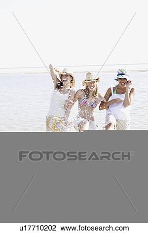 Stock Image - Friends splashing in ocean. Fotosearch