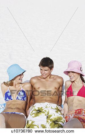 Stock Image - Friends sunbathing on beach. Fotosearch