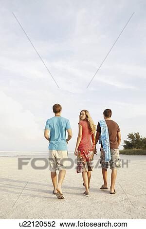 Stock Image - Friends walking on beach. Fotosearch