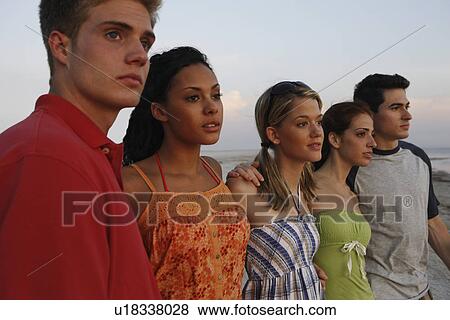 Stock Photo - Friends watching sunset on beach. Fotosearch