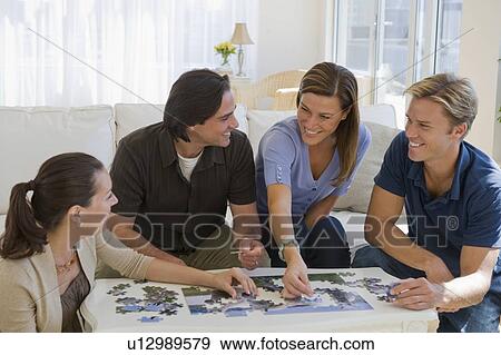 Stock Photo - Friends working on jigsaw puzzle together. Fotosearch