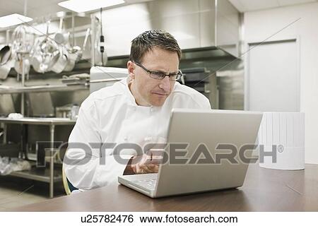 Frustrated chef looking at laptop in kitchen View Large Photo Image Stock Photograph - Frustrated chef looking at laptop in kitchen. Fotosearch