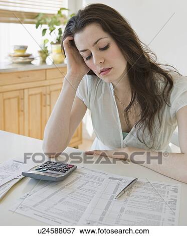 Frustrated woman looking at tax forms View Large Photo Image Stock Photo - Frustrated woman looking at tax forms. Fotosearch