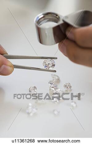 Stock Photo - Gemologist inspecting diamonds using loupe. Fotosearch