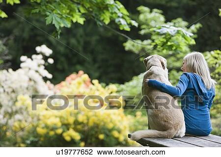 Girl and dog sitting together on picnic table View Large Photo Image Stock Image - Girl and dog sitting together on picnic table. Fotosearch