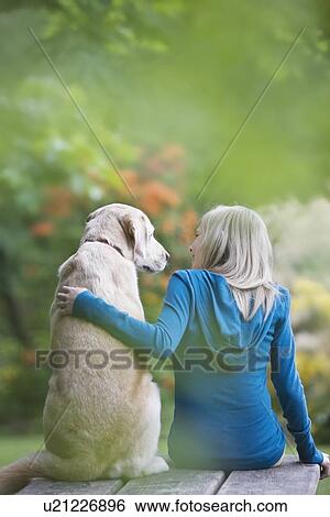 Stock Photograph - Girl and dog sitting together on picnic table. Fotosearch