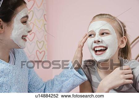 Stock Image - Girl applying facial treatment to friend. Fotosearch