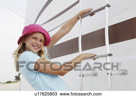 Stock Image - Girl climbing on motor home ladder. Fotosearch