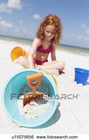 Stock Photograph - Girl digging in sand on beach. Fotosearch