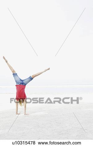 Stock Photo - Girl doing cartwheel on beach. Fotosearch