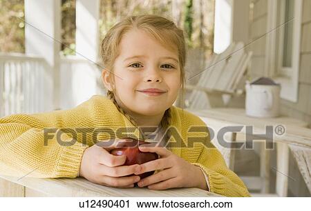 Stock Image - Girl eating apple porch. Fotosearch