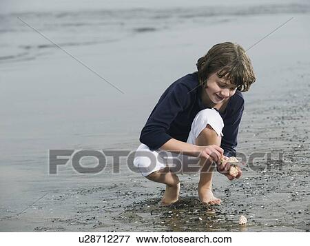 Stock Photo - Girl finding seashells on beach. Fotosearch