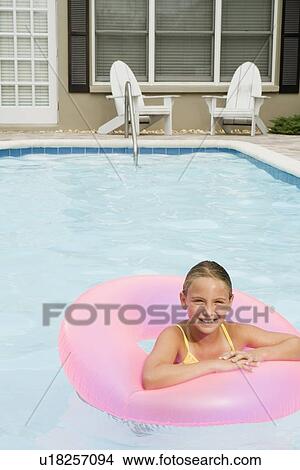 Picture - Girl floating on inflatable ring in swimming pool. Fotosearch
