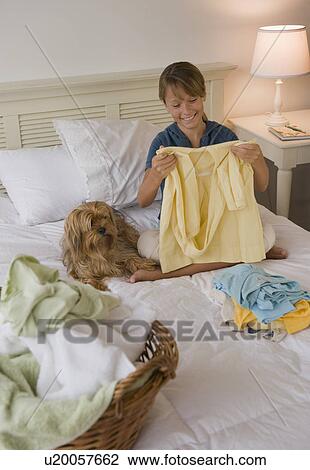 Girl folding clothes on bed View Large Photo Image Stock Image - Girl folding clothes on bed. Fotosearch