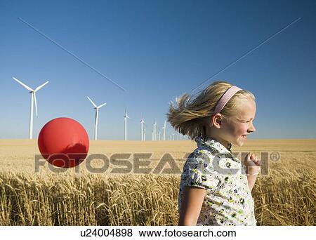 Stock Photo - Girl holding balloon on wind farm. Fotosearch