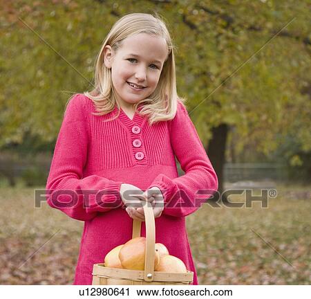 Stock Image - Girl holding basket of apples. Fotosearch