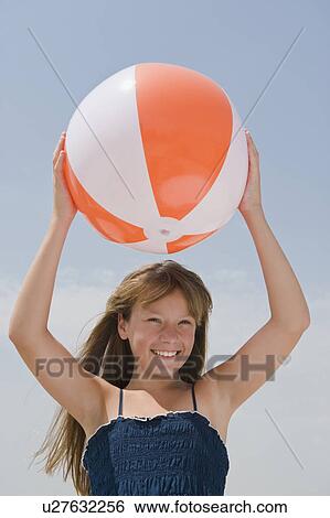 Stock Photograph - Girl holding beach ball above head. Fotosearch