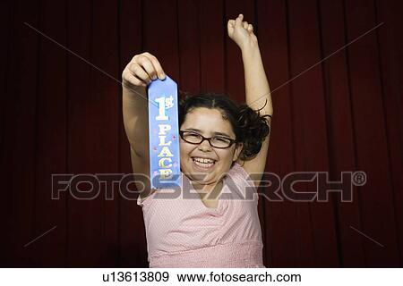 Girl holding first place ribbon on stage View Large Photo Image Stock Photo - Girl holding first place ribbon on stage. Fotosearch