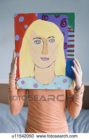 Girl holding painting in front of face View Large Photo Image Stock Image - Girl holding painting in front of face. Fotosearch