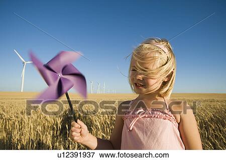 Girl holding pinwheel on wind farm View Large Photo Image Stock Photo - Girl holding pinwheel on wind farm. Fotosearch
