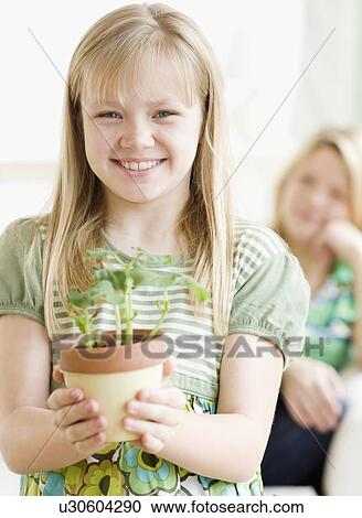 Stock Image - Girl holding potted plant. Fotosearch