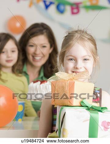 Picture - Girl holding stack of birthday gifts. Fotosearch