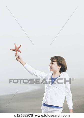 Girl holding starfish on beach View Large Photo Image Stock Photograph - Girl holding starfish on beach. Fotosearch
