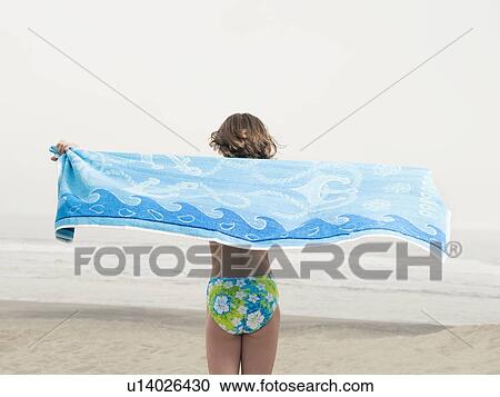 Stock Image - Girl holding towel on beach. Fotosearch