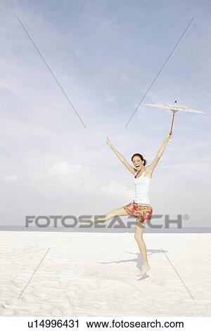 Girl holding umbrella and dancing on beach View Large Photo Image Stock Image - Girl holding umbrella and dancing on beach. Fotosearch