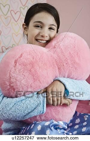 Stock Photo - Girl hugging heart pillow. Fotosearch