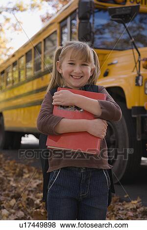 Girl hugging school book in front of school bus View Large Photo Image Stock Photo - Girl hugging school book in front of school bus. Fotosearch
