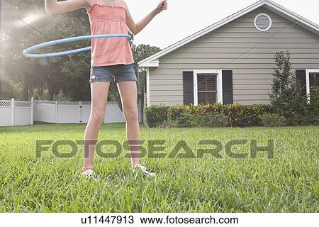 Stock Image - Girl hula hooping in backyard. Fotosearch