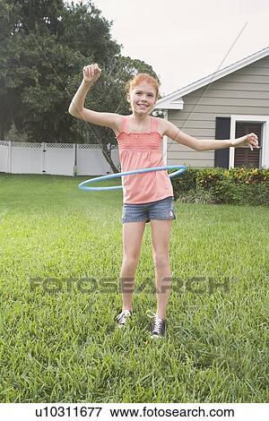 Stock Photo - Girl hula hooping in backyard. Fotosearch