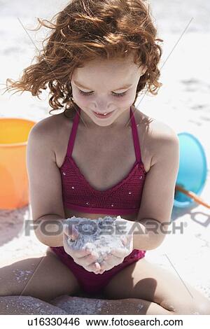 Girl in bikini cupping sand on beach View Large Photo Image Stock Photograph - Girl in bikini cupping sand on beach. Fotosearch