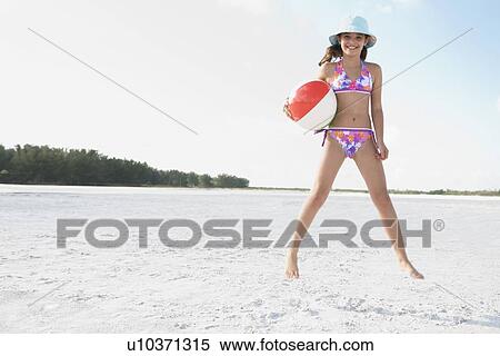 Girl jumping on beach with beach ball View Large Photo Image Stock Photography - Girl jumping on beach with beach ball . Fotosearch
